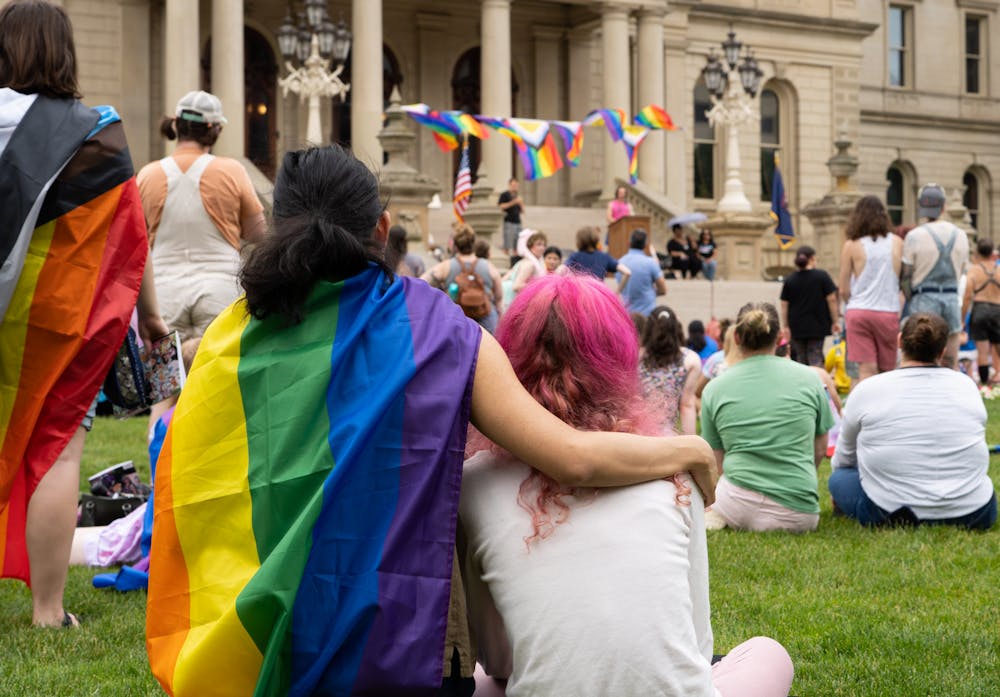 <p>A couple embraces on the lawn of the capitol during a speech at the Lansing pride rally on June 26, 2022.</p>