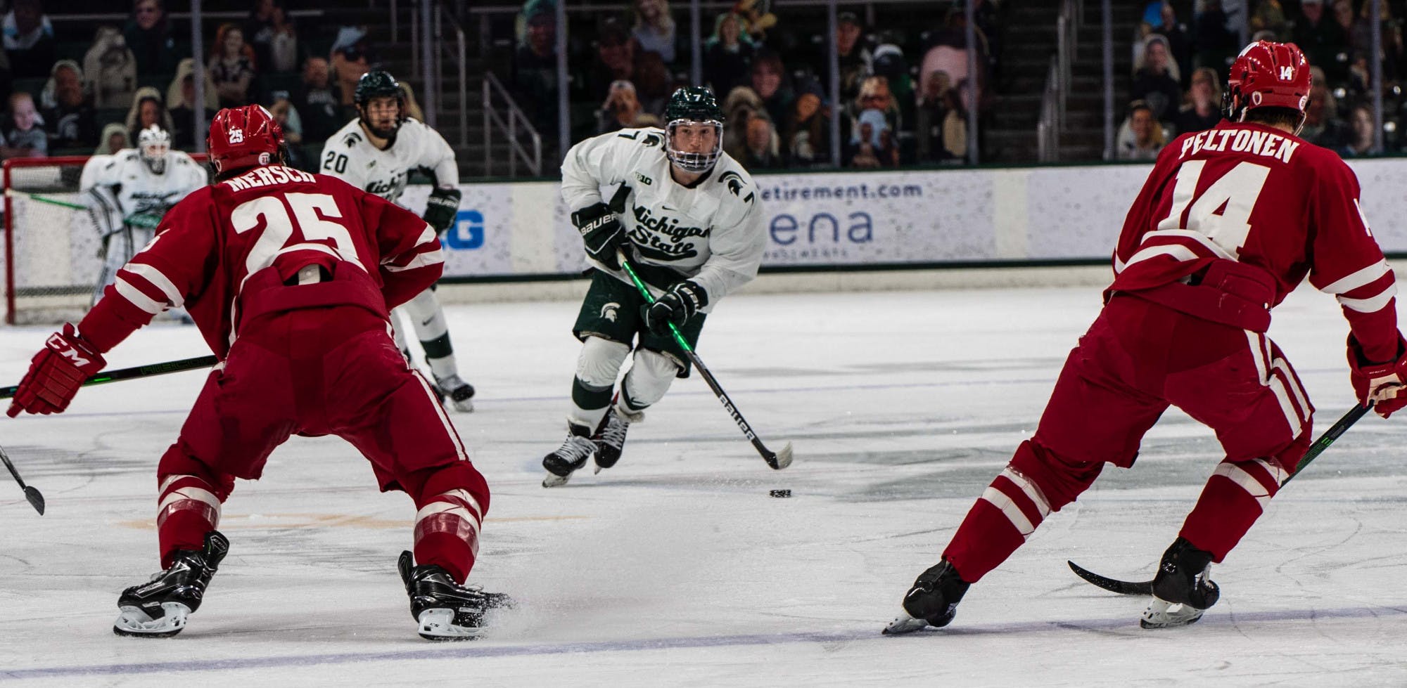 <p>Graduate student forward Charlie Combs (7) takes the puck back from the Michigan State goaltender and skates down the ice in the first period. The Badgers shut out the Spartans 4-0 at Munn Ice Arena on March 5, 2021. </p>