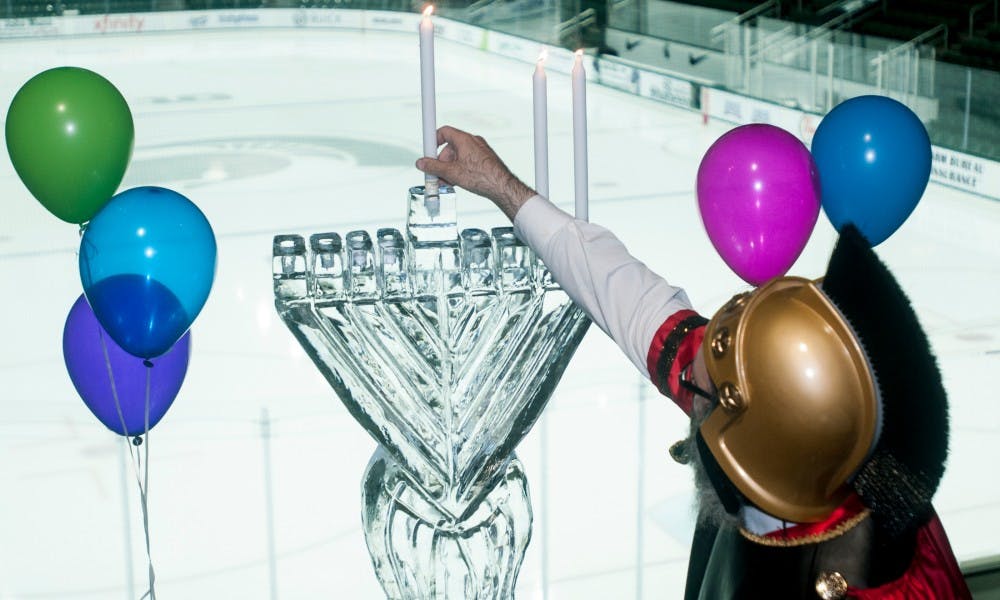 Rabbi Hendel Weingarten lights a menorah made of ice during a Hanukkah celebration hosted by the Chabad House called "Chanukah on Ice" on Dec. 7, 2015 at Munn Ice Arena. The menorah's nine candle places are symbolic of the eight days of Hanukkah and one extra candle to light the others.