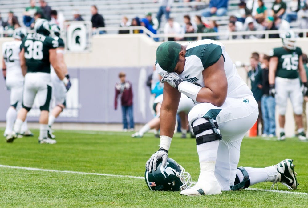 	<p>Senior offensive lineman Arthur Ray Jr. bows his head Saturday at Spartan Stadium before the start of the Spring Game. Ray was able to return to the team to play after recovering from bone cancer. The Spring Game marked the first time he was able to play at Spartan Stadium. Matt Radick/The State News</p>