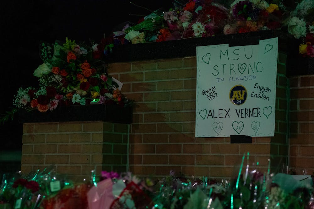 <p>Flowers and a poster in remembrance of Alexandria Verner, one of the three victims of the 2023 campus shooting, surround the Spartan Statue. One year after the Michigan State University campus shooting, a remembrance ceremony was held to remember and reflect on the tragedy.</p>