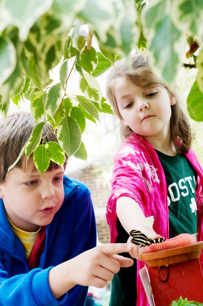 Jorgen Obinger, 6, right, and Hollan Obinger, 9, left, of Chicago, catch butterflies landing in nectar Tuesday afternoon at the Indoor 4-H Children's Garden in Plant and Soil Sciences Building as a part of "Butterflies in the Garden." Until April 30th, the Butterfly House will be open to the public for butterfly interaction. Samantha Radecki/The State News