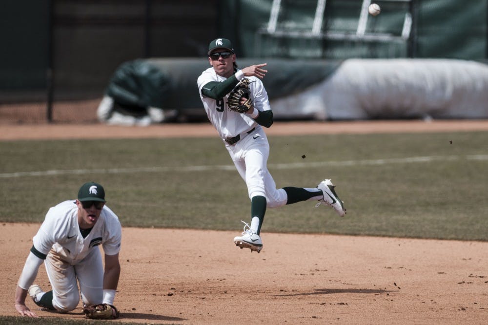 Freshman short stop Ryan king (9) makes a jumping throw to first during the game against the University of Michigan on March 24, 2018 at McLane Baseball Stadium. The Spartans fell to the Wolverines, 3-1. (C.J. Weiss | The State News)
