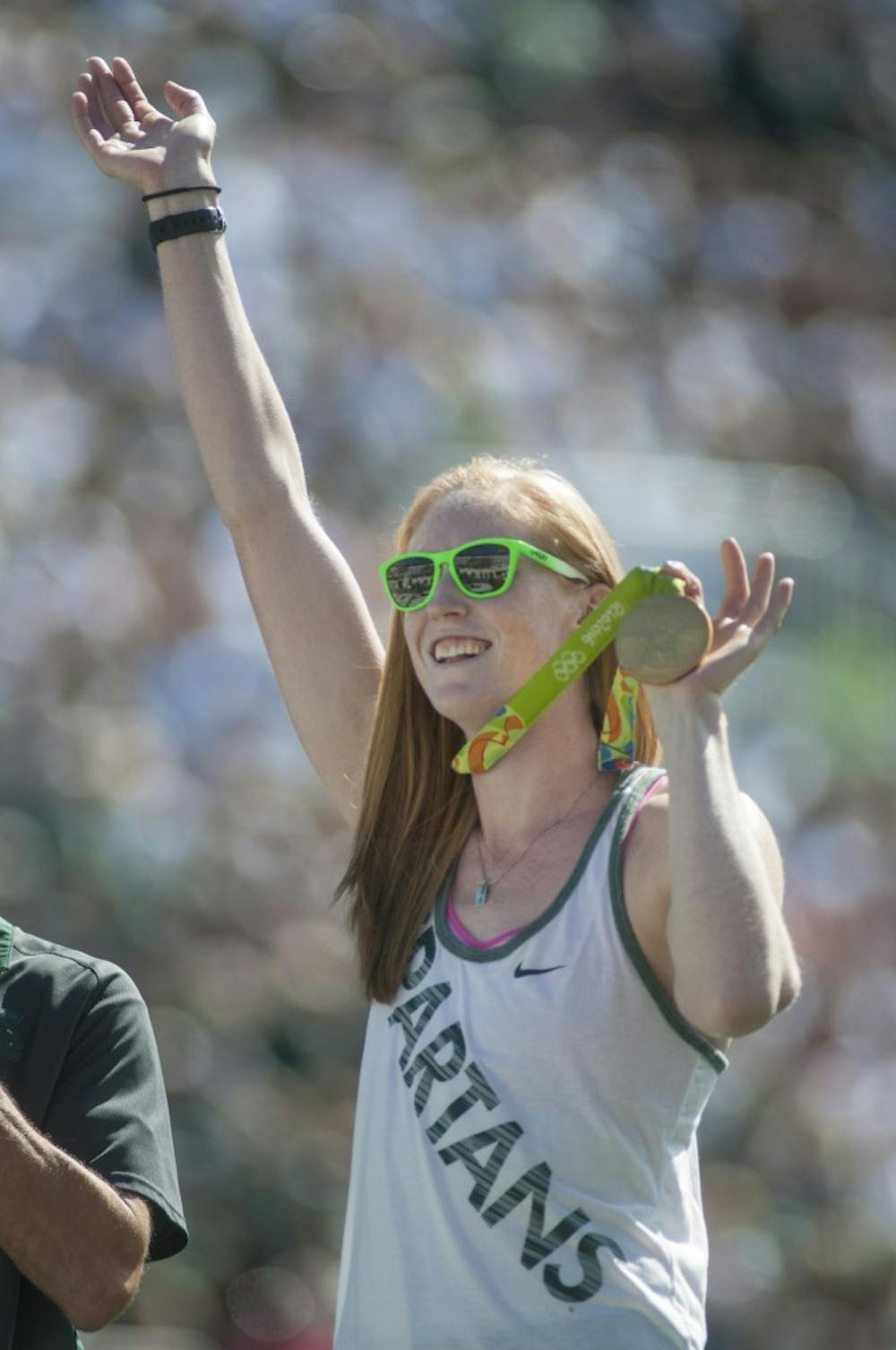 MSU alumna Emily Regan displays her gold medal on the field during the game against Wisconsin on Sept. 24, 2016 at Spartan Stadium. Regan won gold in rowing and was accompanied on the field by head coach of the MSU womens rowing team Matt Wise.