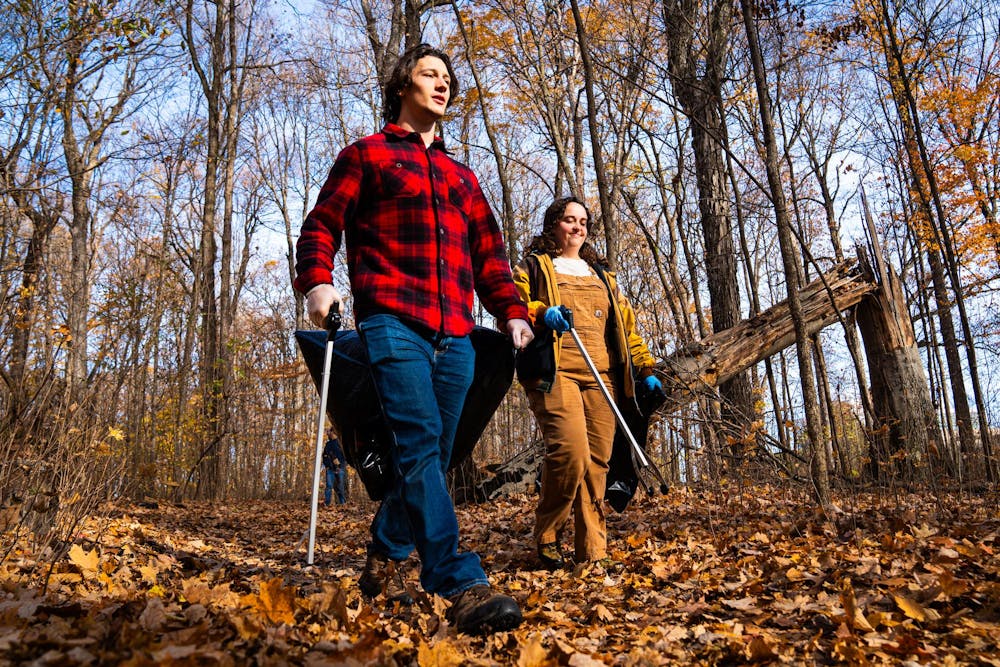 Two students scour the area for loose trash at the Baker Woodlot on Nov. 9, 2024.