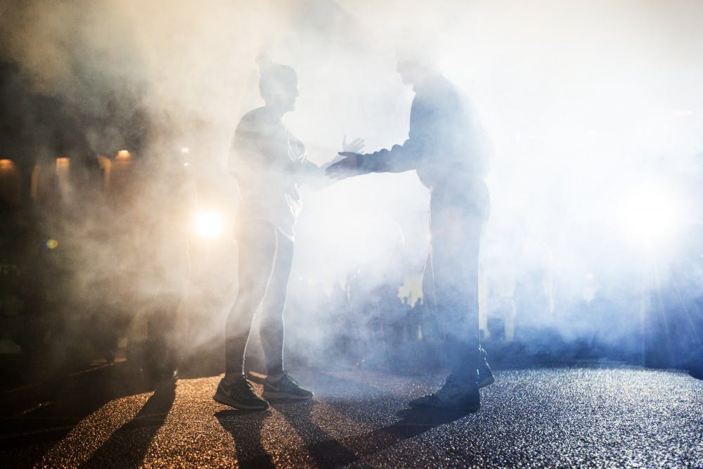 Junior gymnast Tessa Jaranowski, left, and sophomore 133-pounder Austin Eicher go to slap hands during their introduction before the 2nd annual Tumbles and Takedowns event began on Jan. 20, 2017 at Jenison Field House. Tumbles and Takedowns is an event in which the MSU gymnastics and MSU wrestling team simultaneously compete in the Jenison Field House. The Spartan gymnasts were defeated by the Golden Gophers, 193-193.875. The Spartan wrestlers were defeated by the Chippewas, 12-23.