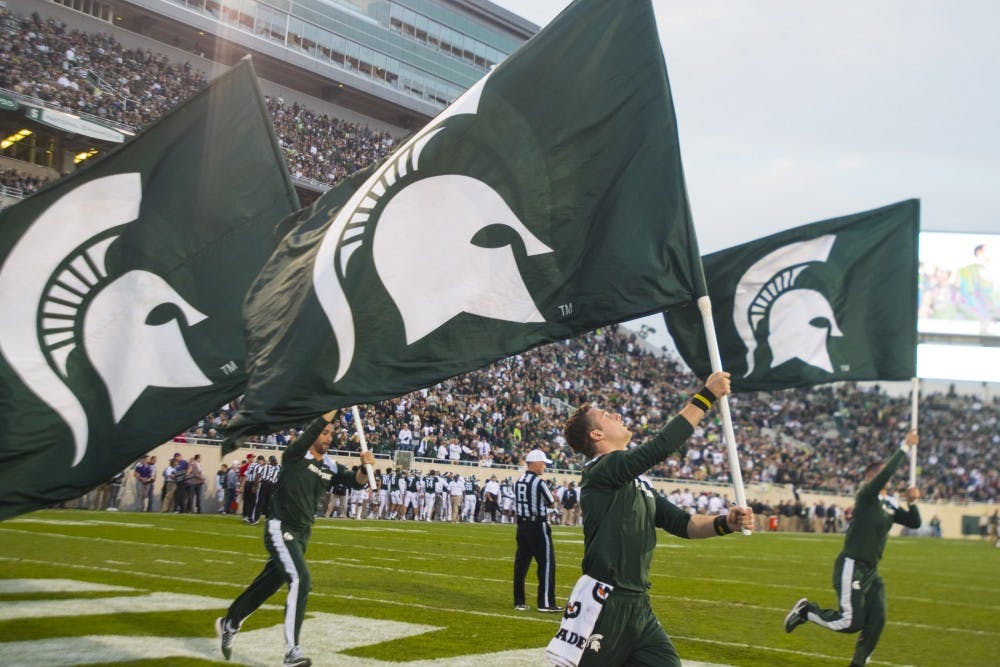 Cheerleaders run with flags after an MSU touchdown during the game against Northwestern on Oct. 15, 2016 at Spartan Stadium.  The Spartans were defeated by the Wildcats, 54-40.  