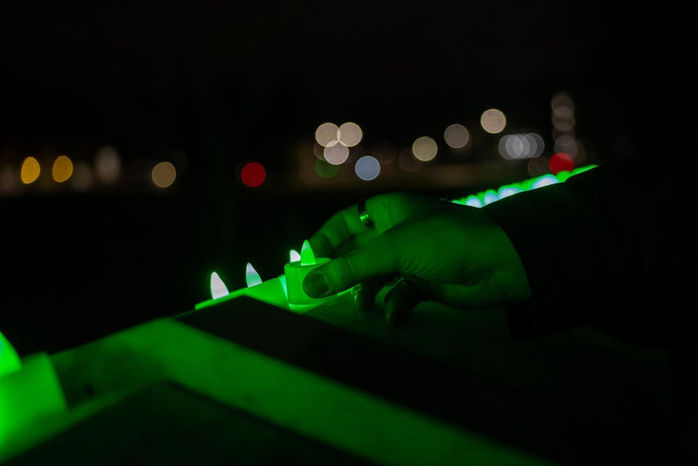 <p>An MSU student places a green light into a row full of them on Feb. 13, 2024. One year after the Michigan State University campus shooting, a remembrance ceremony was held to remember and reflect on the tragedy.</p>
