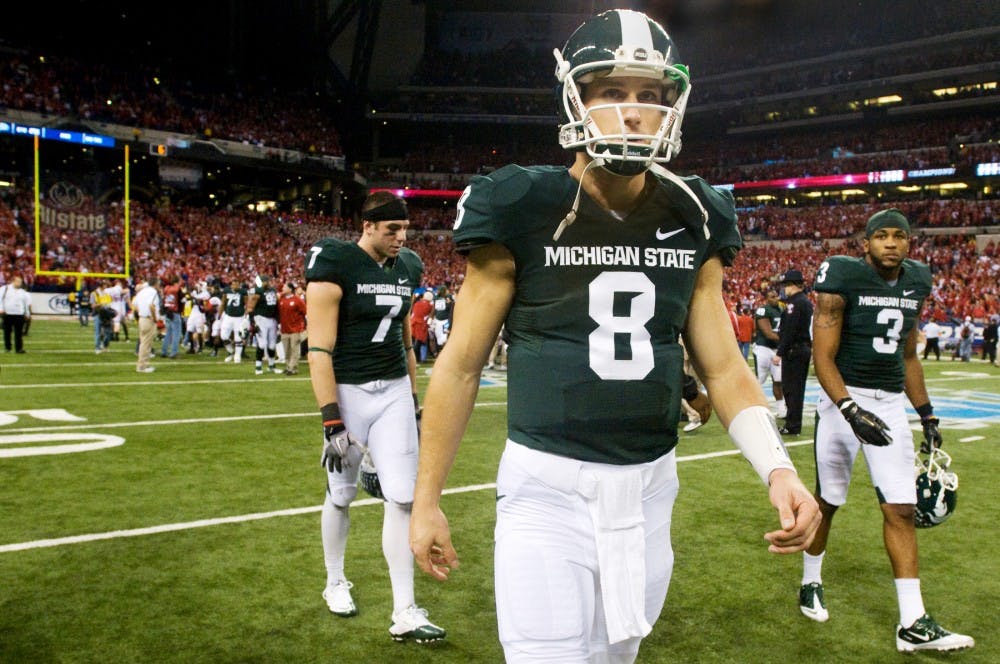 Senior quarterback Kirk Cousins, front, walks off the field, trailed by senior wide receivers Keith Nichol, left, and B.J. Cunningham. The Wisconsin Badgers defeated the Spartans, 42-39, Saturday night at Lucas Oil Stadium in Indianapolis. Justin Wan/The State News