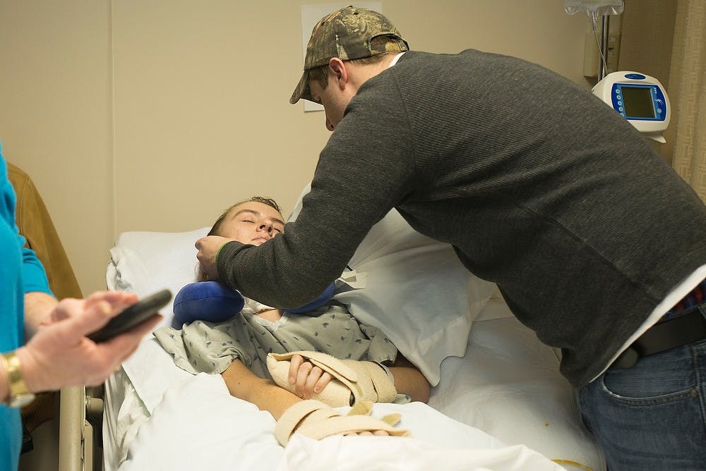 <p>Her fiancé Brandon Childers tucks MSU graduate Stacy Blakeslee's hair behind her ear March 5, 2014, at Spectrum Rehab and Nursing Center, 4118 Kalamazoo Ave., in Grand Rapids. Childers spends most days with Blakeslee in the hospital. He said he can tell she's more calm when he's around. Julia Nagy/The State News</p>