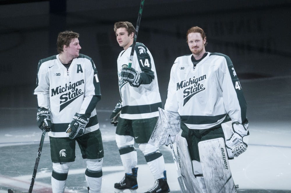 Senior's Carson Gatt (18), Dylan Pavelek (14), and Ed Minney (45) acknowledge the crowd in the middle of the ice during senior night on Feb. 17, 2018 at Munn Ice Arena. (C.J. Weiss | The State News)