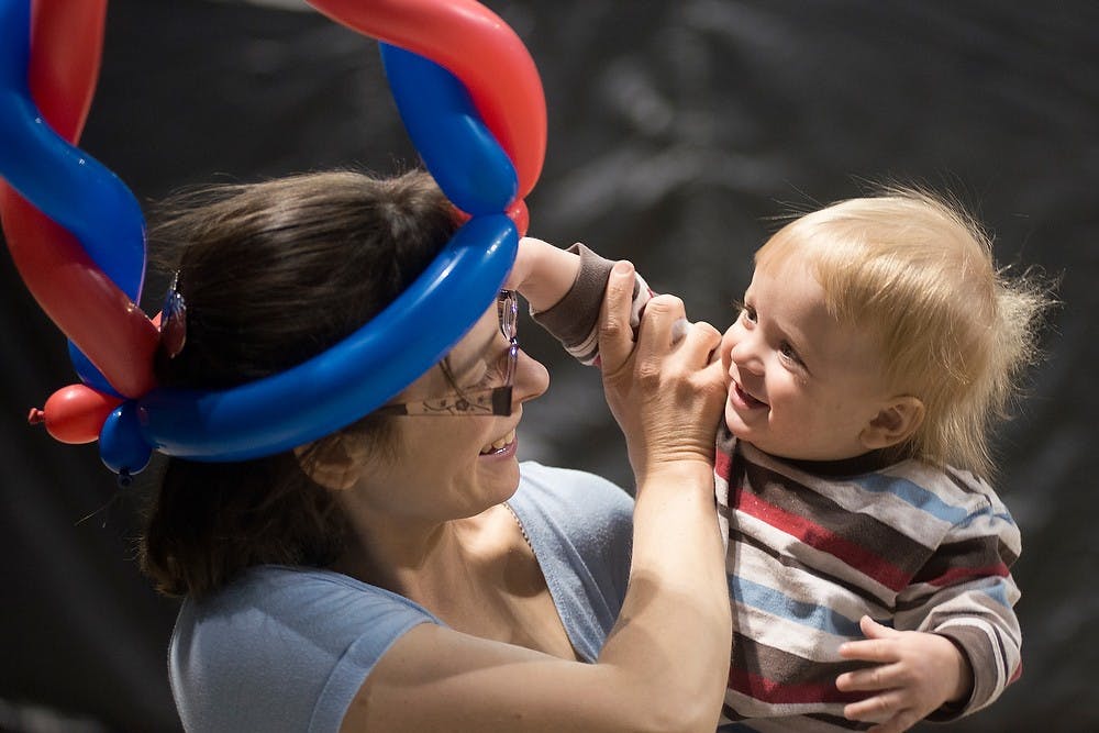 <p>Lansing resident Charles Klaiss, 1, reaches for his mother's, Kayitlyn, balloon hat April 19, 2014, at the Breslin Center. Kayitlyn was there with her children to enjoy the Breslin Takeover Carnival and Resource Fair, which included laser tag and a petting zoo. Julia Nagy/The State News</p>