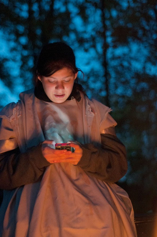 	<p>Biosystems engineering freshman Karley Rivard, who plays a demon virgin sacrifice in the haunted hayride, sits beside the fire and checks her phone in the woods on Oct. 12, 2012, at Sundance Riding Stables in Grand Ledge. Natalie Kolb/The State News</p>