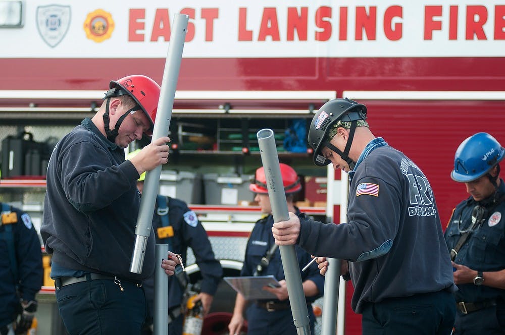 <p>Firefighter Chris Wilcox, left, and engineer Tim Garver set up equipment for rescue training on Sept. 16, 2014, by Service Road and Farm Lane. Fire departments from Lansing and surrounding cities are attending training from Sept. 16-18. Aerika Williams/The State News </p>