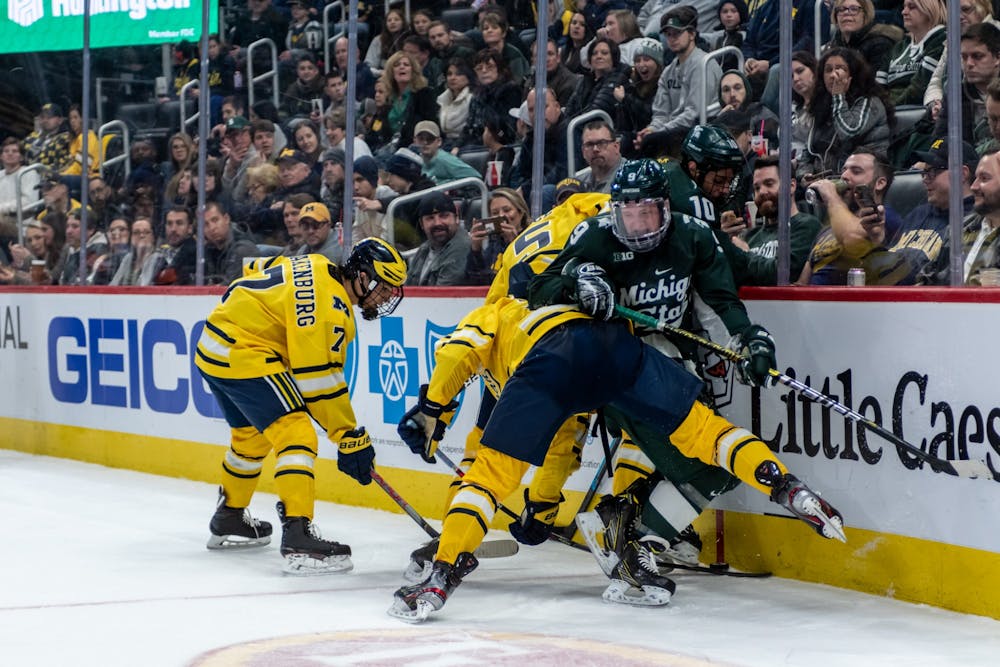 Junior left wing Mitchell Lewandowski (9) and senior right wing Sam Saliba (10) battle with Michigan players for a puck against the boards. The Spartans fell to the Wolverines, 1-4, at Little Caesars Arena on February 17, 2020. 