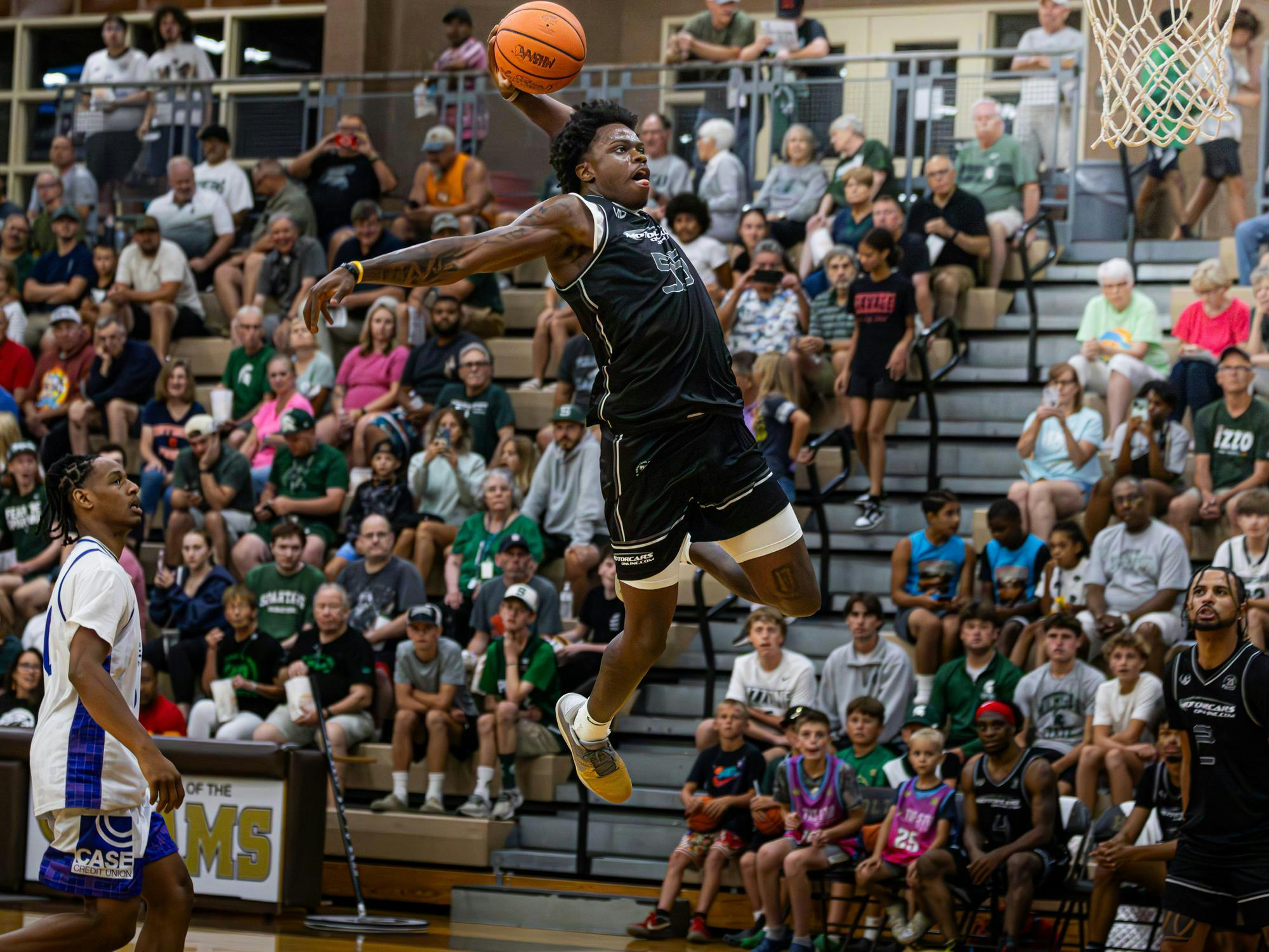 Junior forward Coen Carr (55) takes flight for a dunk against Team Case Credit Union at the Moneyball Pro-Am at Holt High School on July 22. Carr led all scorers with 40 points and three three-pointers.