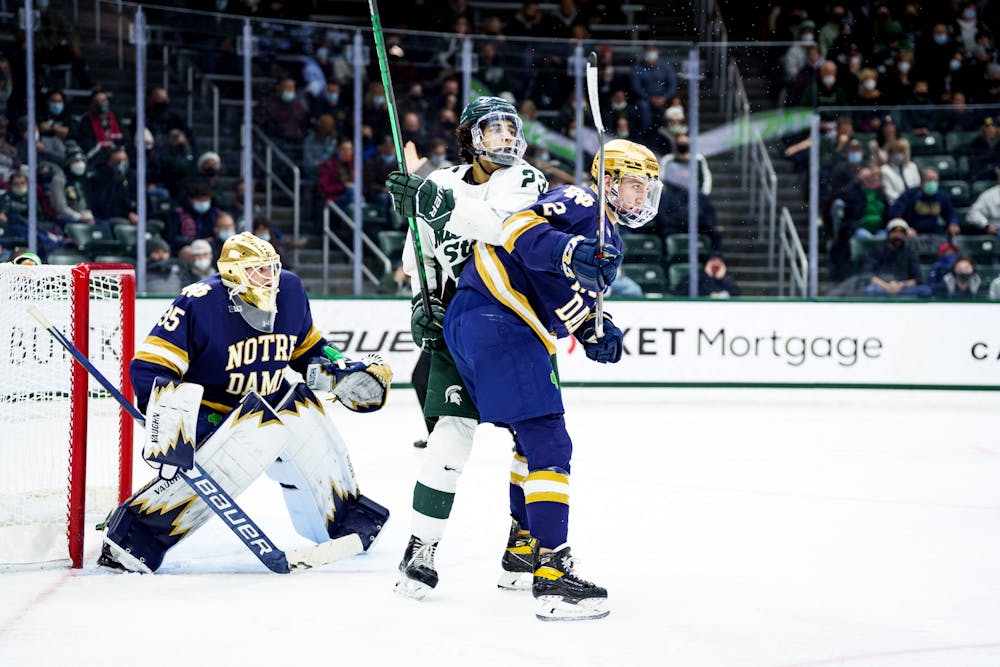 <p>Michigan State junior Jagger Joshua and Notre Dame graduate student Jack Adams at odds with each-other while waiting for the puck with Notre Dame graduate student Matthew Galajda behind them in goal on Feb. 19, 2022. Spartans lost 4-2 against Notre Dame.</p>