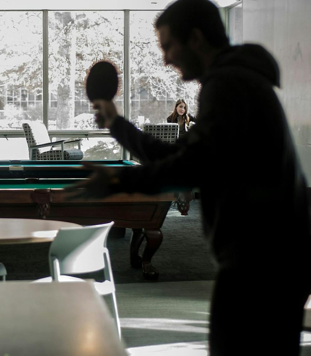 <p>Economics freshman Raffi Hulian begins a match of ping pong Sunday afternoon, while a student observes at Akers Hall. Kayla Clarke/The State News.</p>