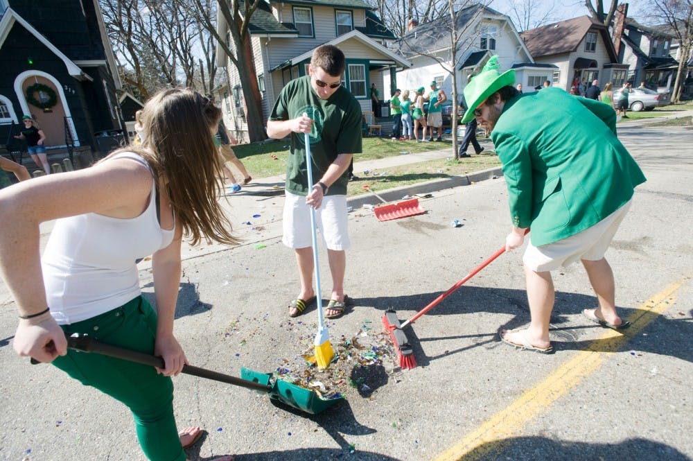 From left, advertising senior Lauren Armstrong, East Lansing resident Jeff Sloan, and supply chain senior Joe Bostwick clean up trash on Saturday afternoon on Collingwood Drive. Police responded to the incident after beer bottles and other items were thrown on the street. Justin Wan/The State News