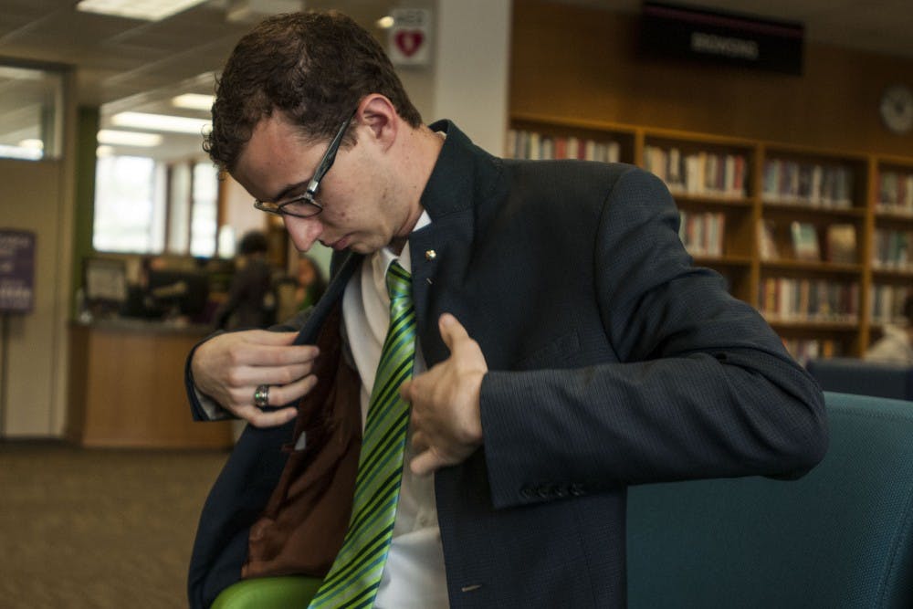 <p>President of the Associated Students of Michigan State University Lorenzo Santavicca puts on his jacket prior to walking to the Hannah Administration Building on April 24, 2018 at the Main Library. (C.J. Weiss | The State News)</p>