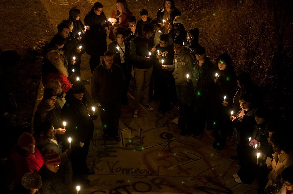 	<p>Students and community members stand with lit candles during a moment of silence during the National Transgender Day vigil, Nov. 20, 2013, beneath the bridge behind The Rock on Farm Lane. Members of <span class="caps">LGBT</span> student associations read off names of victims of gender-based crimes around the world. Danyelle Morrow/The State News</p>