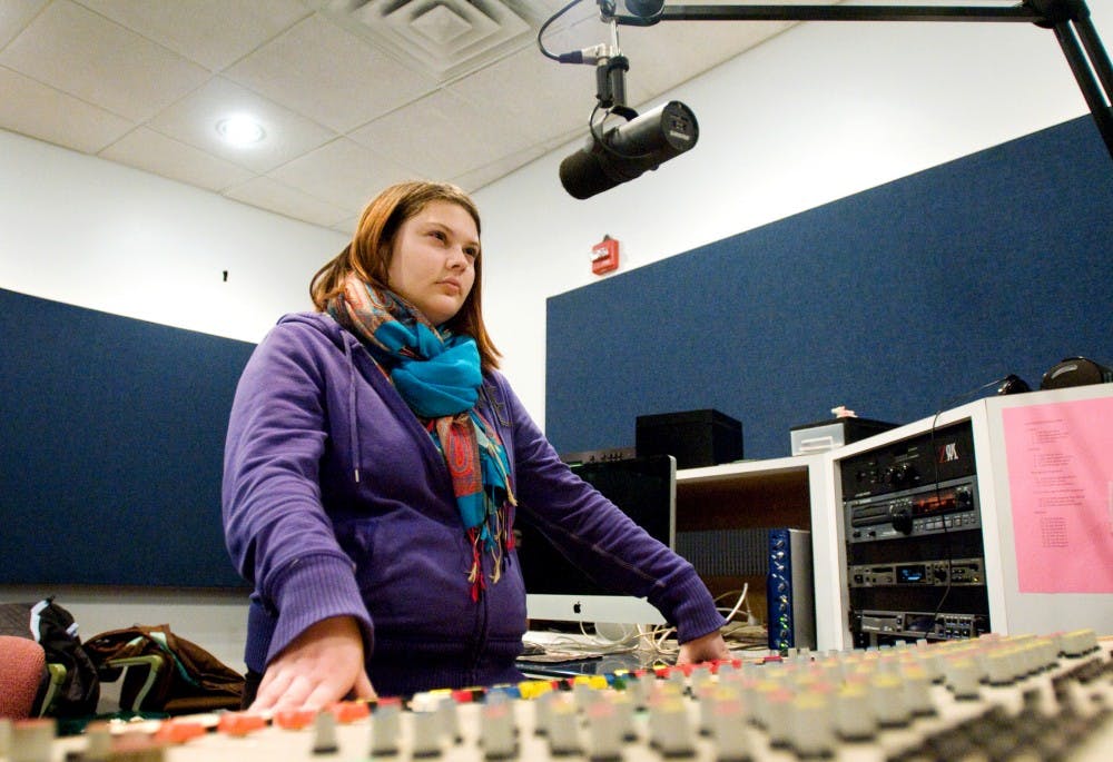 Psychology senior Bernadette Cooper listens from the sound booth to the show "Spartan Sportswrap" on Monday at the studios of 89FM The Impact in the basement of Holden Hall. Cooper has been an audio engineer at the station since her sophomore year. Kat Petersen/The State News