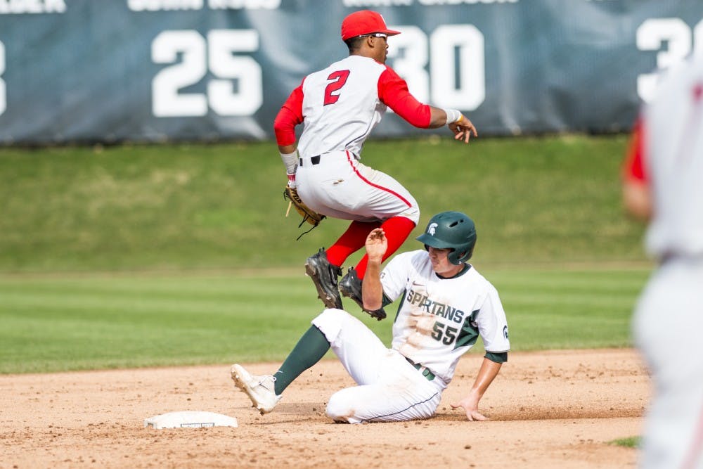 Junior infielder Zack McGuire (55) slides into the base and Ohio State infielder Jalen Washington (2) throws the ball to first base during the game against Ohio State on April 14, 2017 at McLane Baseball Stadium at Kobs Field. The Spartans defeated the Buckeyes, 2-0.