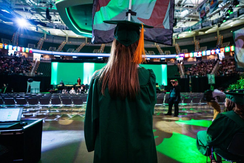 <p>An MSU alumnus prepares to march onto the floor with her college's flag during the fall 2024 commencement ceremony at the Breslin Center on Dec. 14, 2024.</p>