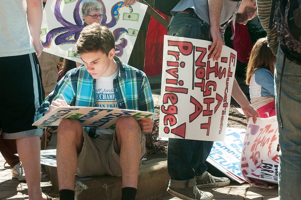 <p>Chinese sophomore Marcus Windel draws on a sign before a protest against tuition hikes hosted by MSU Students United on April 11, 2014, at Beaumont Tower. Students marched through campus down to the state Capitol. Danyelle Morrow/The State News</p>