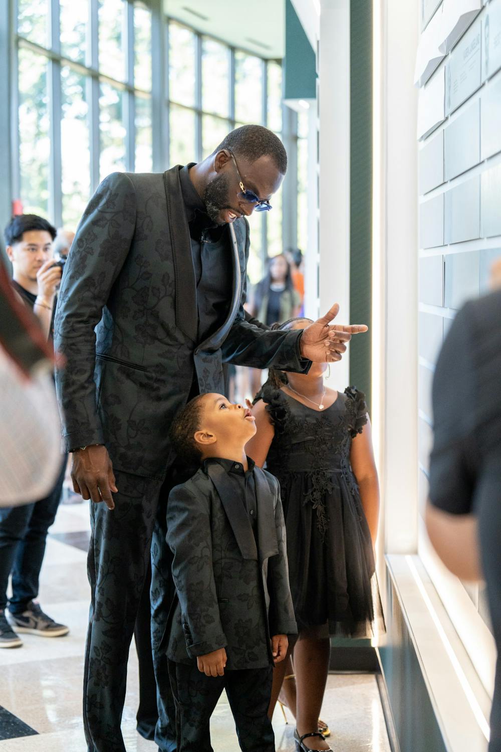 <p>2022 Inductee to the MSU Athletics Hall of Fame Draymond Green shows his son the wall of dedicated plaques, on Sept. 9, 2022.﻿</p>