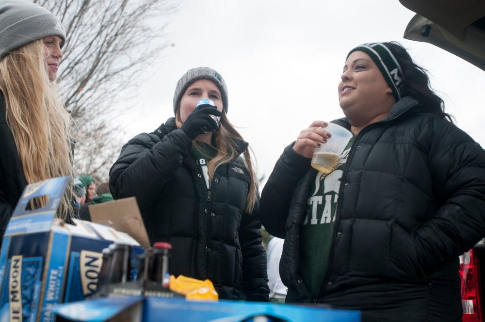 <p>From left, alumna Ann Kennedy, Sara Hess, and Kristen Kenyon drink beer before the game on Nov. 8, 2014, near the tennis courts on MSU's campus. The Michigan State Spartans take on the Ohio State Buckeyes. Aerika Williams/The State News </p>