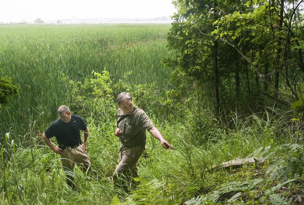 Plant biology professor Frank Telewski points out a spot for Ludington, Mich. Detective J.B. Wells at Suttons Landing Park in Pere Marquette Charter Township, Mich. on July 19, 2012 as the pair gather evidences for a murder investigation. Telewski was invited to utilize his scientific profession in attempt to trace back to the location of the incident. Justin Wan/The State News