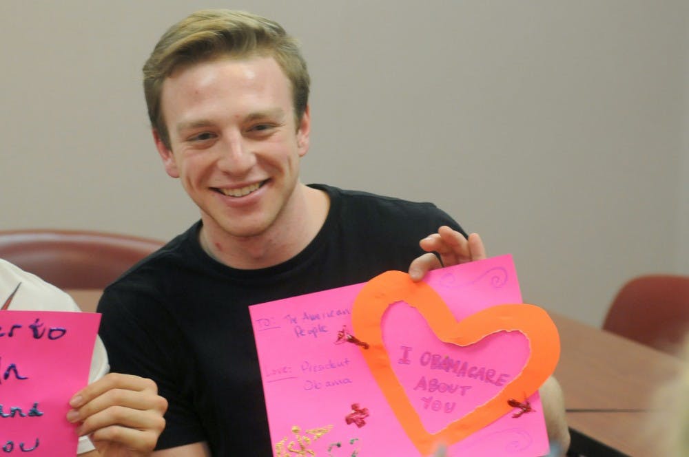 Student relations and policy junior Dan Eggerding holds up a political themed Valentine's Day card while a friend takes his picture at an MSU College Democrats meeting on Feb. 8, 2016 at Case Hall. Eggerding is the communications director for the MSU College Democrats.