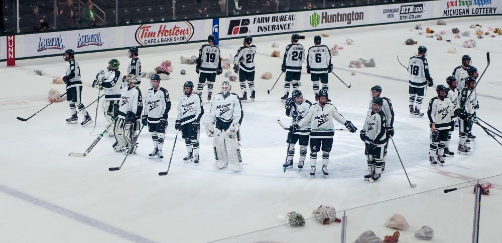 The Spartan hockey team watches as fans throw stuffed animals onto the ice after the game against Wisconsin on Dec. 12, 2015 at Munn Ice Arena. The stuffed animals were collected and donated to children's charities in the Lansing area. 