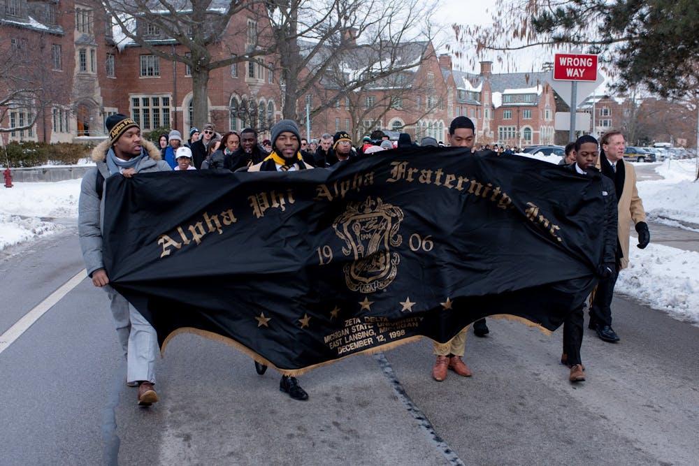 Members of the Alpha Phi Alpha fraternity hold up their banner during the MLK march on MSU's campus on January 20, 2020. Alpha Phi Alpha lead the march through campus. 