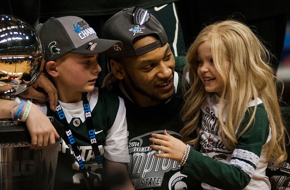 <p>Then-senior forward Adreian Payne holds St. Johns Mich., resident Lacey Holsworth, 8, and head coach Tom Izzo's son Steven Izzo, left, March 16, 2014, after the game against Michigan at the Big Ten Championship at Bankers Life Fieldhouse in Indianapolis. The Spartans defeated the Wolverines, 69-55. Erin Hampton/The State News</p>