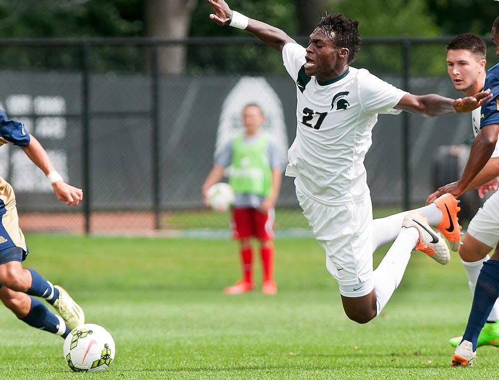 <p>Senior midfielder Fatai Alashe takes a fall while pushing through Florida International midfielder Donald Tomlinson Aug. 31, 2014, at DeMartin Soccer Stadium at Old College Field. The Spartans defeated the Panthers, 3-0. Raymond Williams/The State News</p>