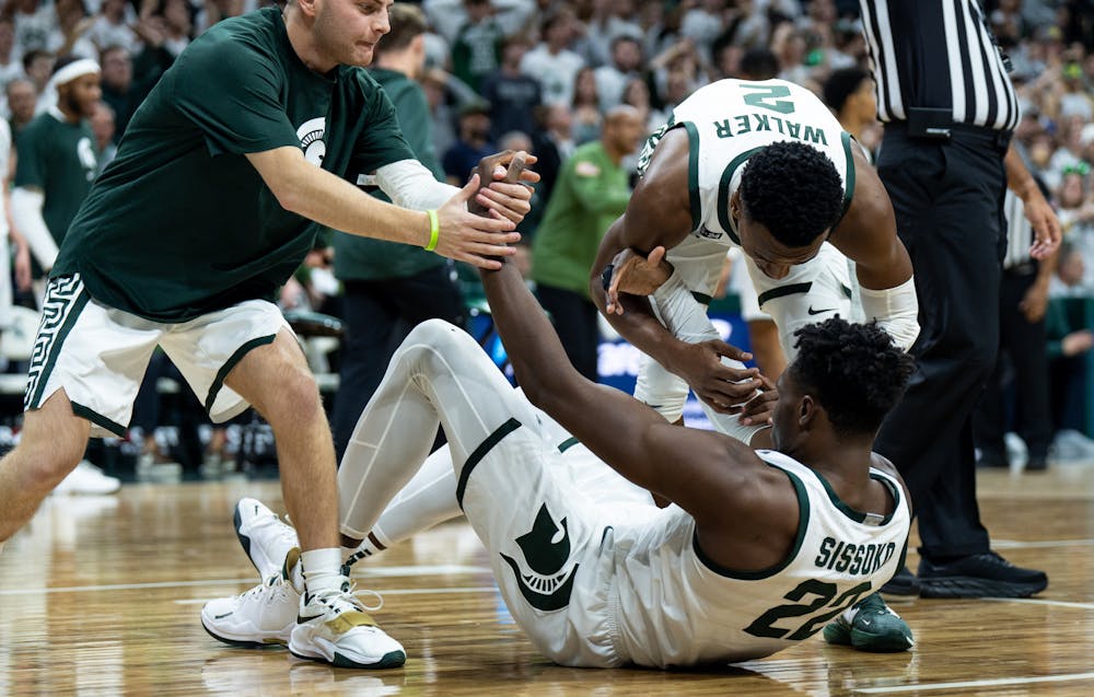 <p>Senior guard Steven Izzo (13) and senior guard Tyson Walker (2) help up junior center Mady Sissoko (22) after he falls down during a game against Villanova at the Breslin Center on Nov. 18, 2022. The Spartans defeated the Wildcats 73-71. </p>