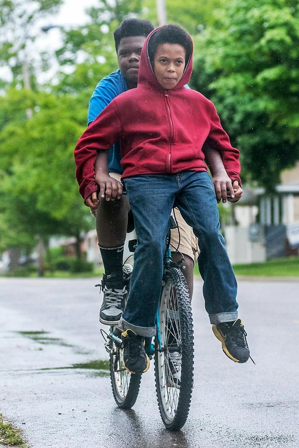 	<p>Linwood Cannon, 12, of Lansing, sits on the bike handlebars as Lansing resident Daequan Thomas, 13, rides the bike en route to West Ottawa Street in Lansing as the two head home, May 27, 2013. &#8220;We don&#8217;t care (about the rain),&#8221; Cannon said. &#8220;We are just having fun.&#8221; Justin Wan/The State News</p>