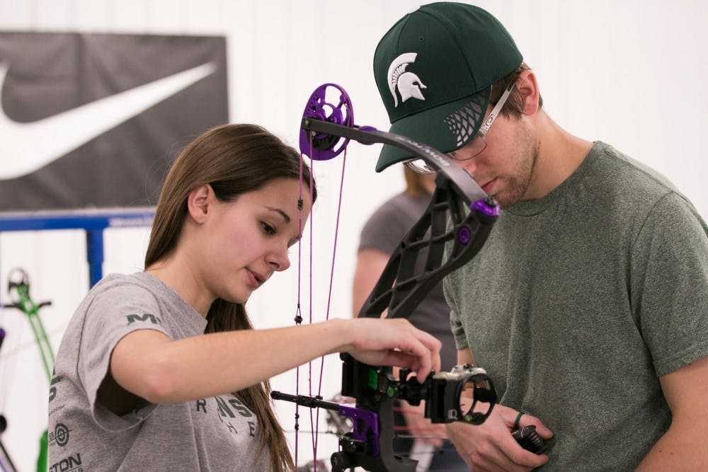 Neuroscience senior Erin Formiller helps junior packaging Nick Hool with his bow April 6, 2016 at Demmer Sports and Education Center in East Lansing.  Hool has been shooting bow for about three and a half years.