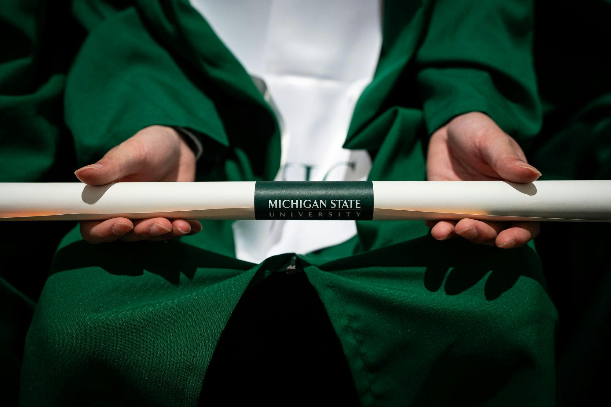 A graduating senior holds their diploma in their hands during commencements at the Breslin Center on May 3, 2025.