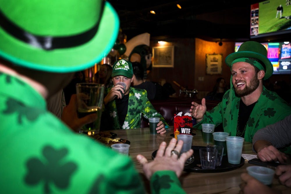 From left to right, graduate student Nick Grundner, advertising senior Logan Page and human biology senior Lee Williamson converse during St. Patrick's Day on March 17, 2017 at Harper's Restaurant and Brew Pub at 131 Albert Ave in East Lansing. "Senior year we gotta go all out we know. Next year we're not gonna be able to do this, we have jobs, you know. We all decided to wake up, we're up at 5:40 this morning, got in line, we're the first guys in line, we're out here putting in some overtime this morning on Saint Patrick's Day," Page said.