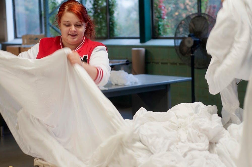 	<p>Lansing resident Tamarie Olson separates sheets Oct. 10, 2013, at the <span class="caps">MSU</span> Linen Services Building. After sheets are dried, they are sent into a machine that presses and folds them to be distributed throughout campus. Margaux Forster/The State News</p>