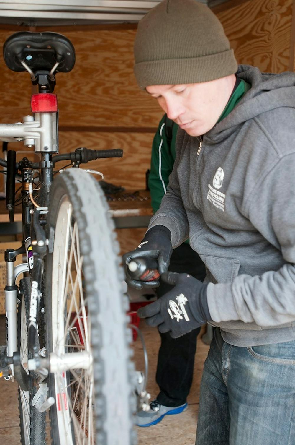 <p>MSU Surplus Store and Recycling Center Sales Manager Tom March repairs a student's bike April 22, 2015, at the Rock on Farm Lane during the Sustainable Spartans' Earth Day Extravaganza. The group handed out free plants and offered free bike repairs in celebration of Earth Day. Kelsey Feldpausch/The State News</p>
