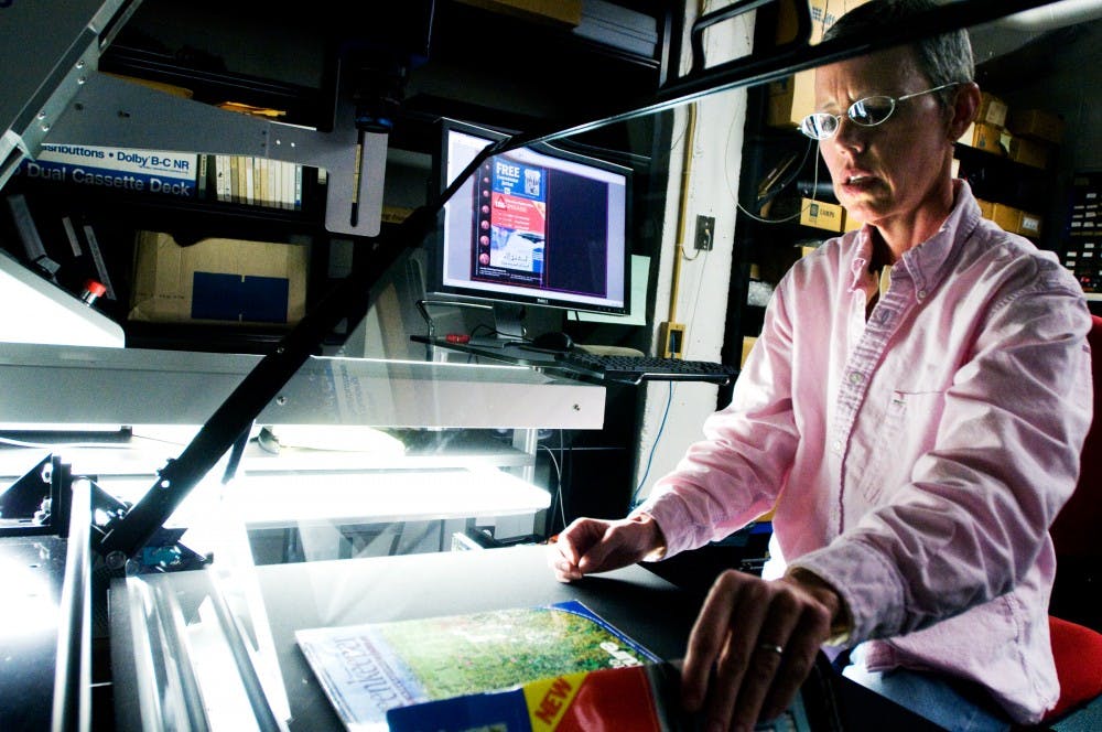 	<p><span class="caps">MSU</span> library employee Laura Carter scans a magazine on the university&#8217;s $130,000 large format scanner in March 2011. Carter is one of the people responsible for digitalizing select works in the library to make them more accessible to the public. State News File Photo</p>