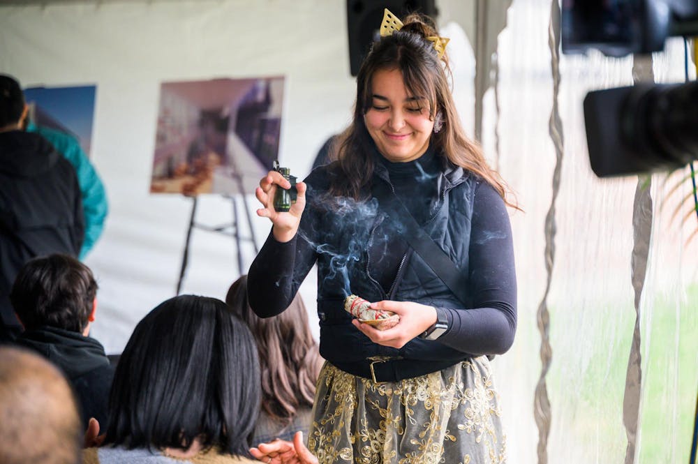 A student burns sage during a groundbreaking ceremony for Michigan State University's new Multicultural Center on April 21, 2023.