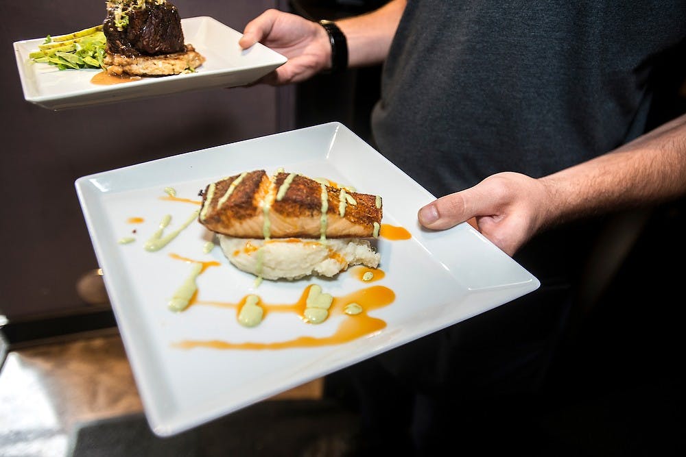 <p>Alumnus and East Lansing resident Seth Zundel serves food July, 30, 2014, at Black Cat Bistro in East Lansing. Zundel graduated with a degree in english in May, 2013 and is currently a server at Black Cat Bistro. Corey Damocles/The State News </p>