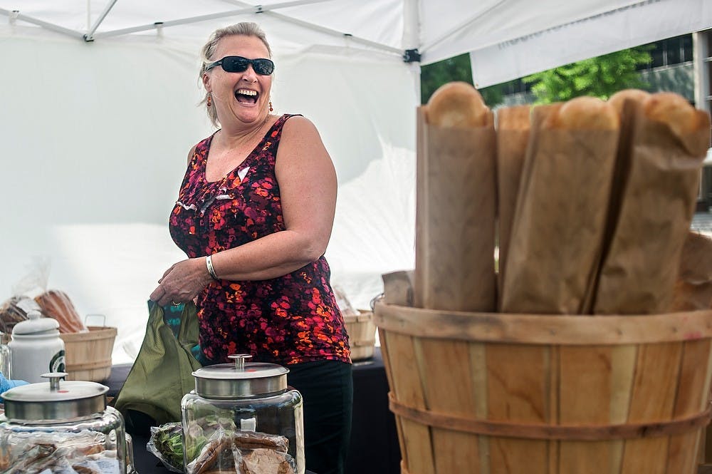 	<p>Kim Graham, a financial analyst at the Facility for Rare Isotope Beams, or <span class="caps">FRIB</span>, laughs as she makes a purchase at the farm stand run by <span class="caps">MSU</span> Bakers, May 30, 2013, on Farm Lane. She said she tries to stop by every Thursday to support the <span class="caps">MSU</span>-affiliated store. Justin Wan/The State News</p>