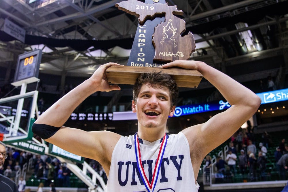 Senior forward T.J. VanKoevering holds the trophy on his head after his team's win in the MHSAA Division 2 boys basketball finals March 16, 2019, at Breslin Center. The Unity Christian Crusaders defeated the River Rouge Panthers, 58-55.