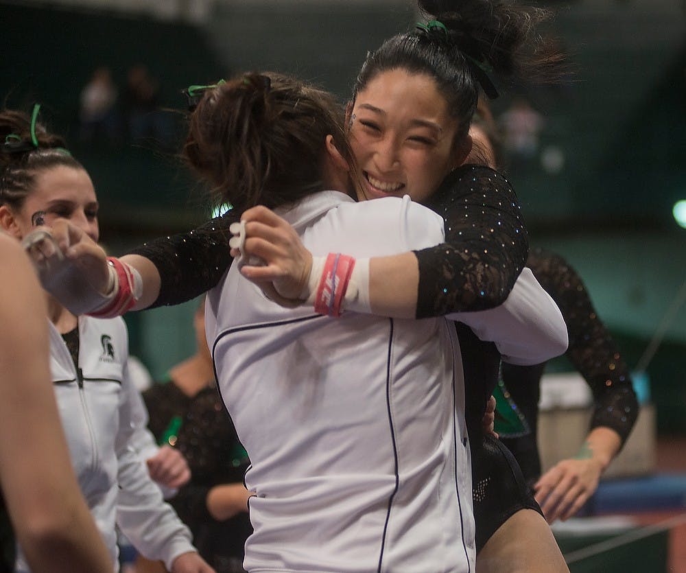 <p>Then-junior Lisa Burt hugs her teammates Feb. 13, 2015, after her performance on the bars at the women's gymnastics meet against Michigan. The State News File Photo</p>